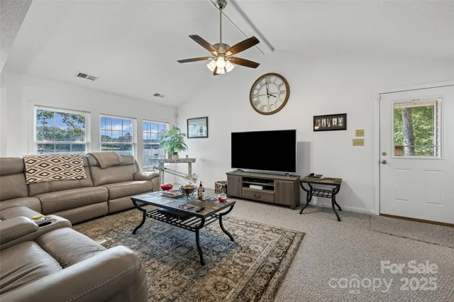 a living room with furniture a clock on wall and a flat screen tv
