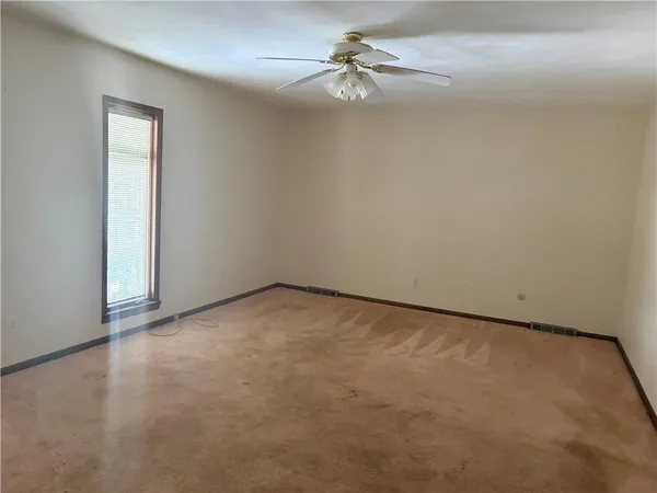 an empty room with a fan & a ceiling fan