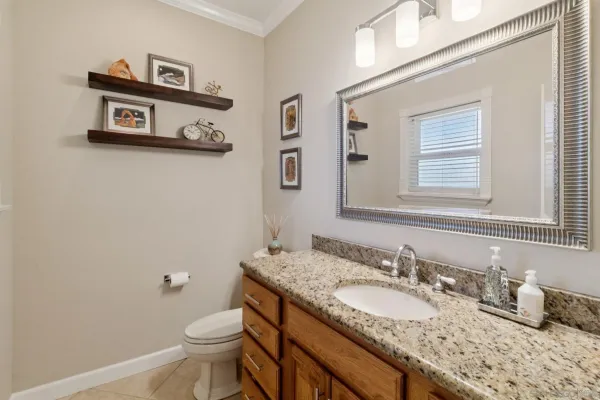 a bathroom with a granite countertop sink mirror vanity and toilet