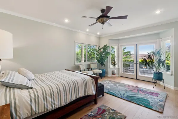 a spacious bedroom with a bed a chandelier and a large window