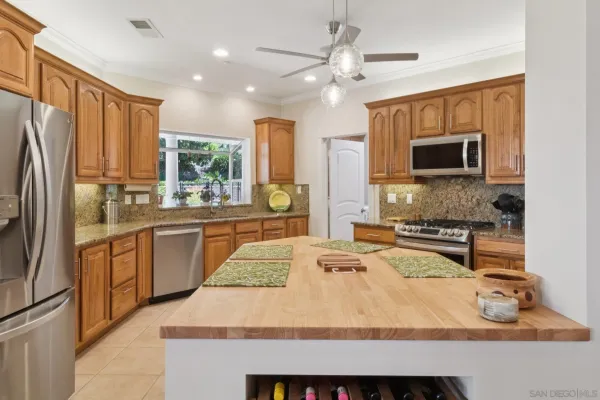 a kitchen with stainless steel appliances granite countertop a refrigerator a stove top oven a sink dishwasher and white cabinets with wooden floor