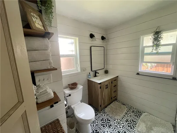 a bathroom with a sink a toilet a window and vanity