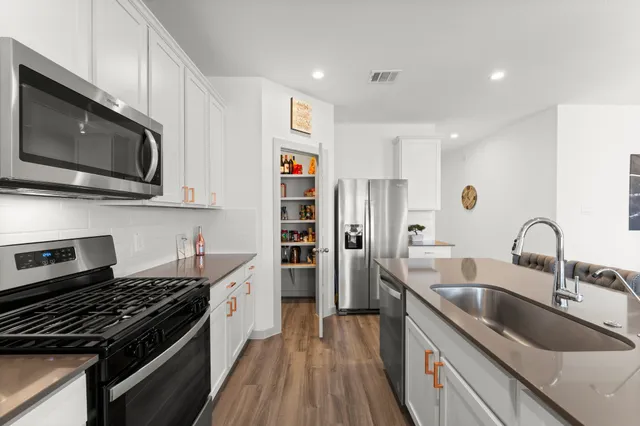 a kitchen with stainless steel appliances a sink a stove and a microwave