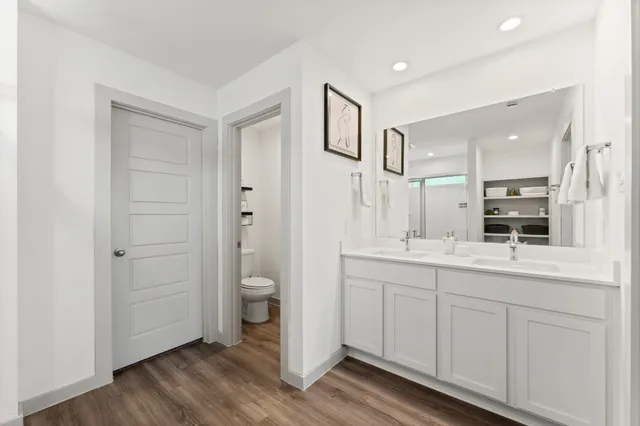 a bathroom with a double vanity sink a toilet and a mirror