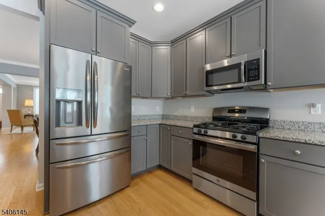 a kitchen with stainless steel appliances white cabinets white stove a microwave and a refrigerator