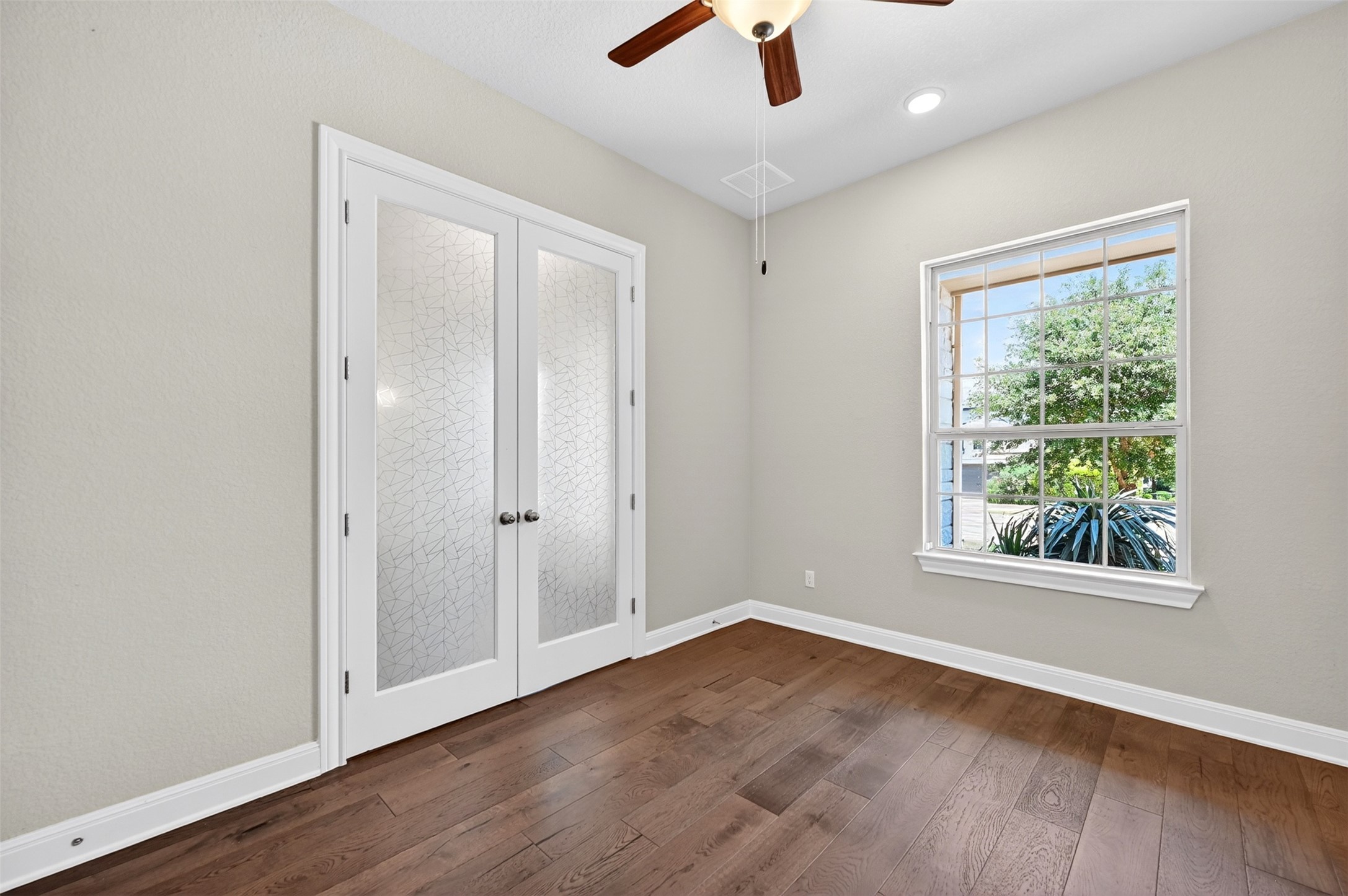 1201 Positano Pass Leander, TX 78641 - Photo 7 of 40 Room featuring wood-finish flooring, a window with exterior landscaping, and double doors with frosted glass panels