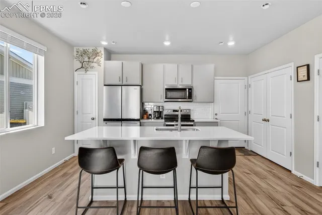 a kitchen with stainless steel appliances a dining table chairs refrigerator and sink