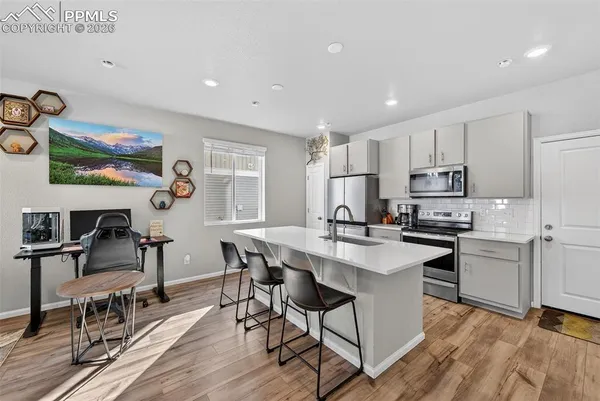 a kitchen with stainless steel appliances granite countertop a table chairs sink and cabinets