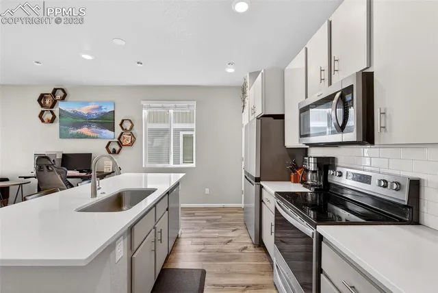 a kitchen with stainless steel appliances a sink a stove a microwave a sink a refrigerator and cabinets