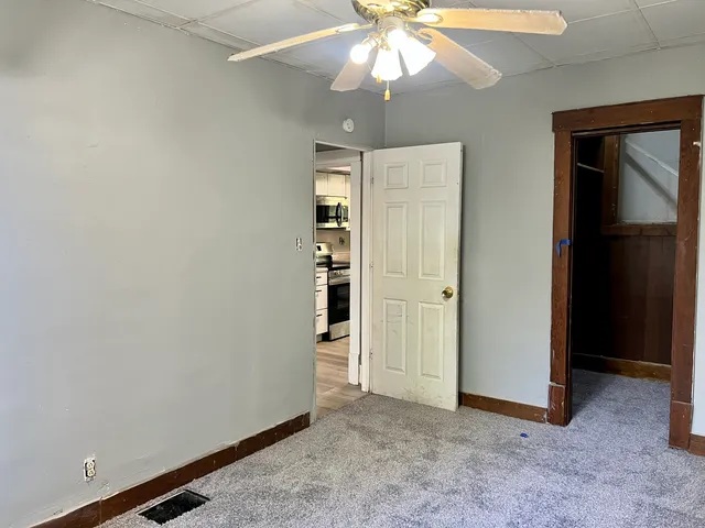 an empty room with closet and a chandelier fan