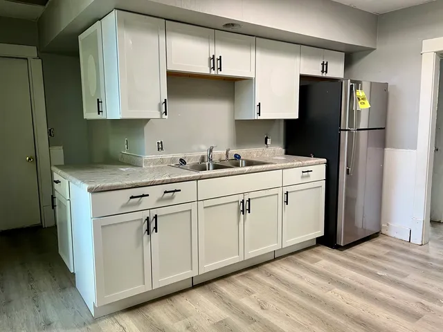 a kitchen with a sink a refrigerator and cabinets