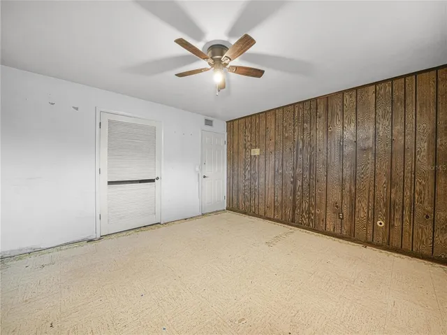 an empty room with windows and fan