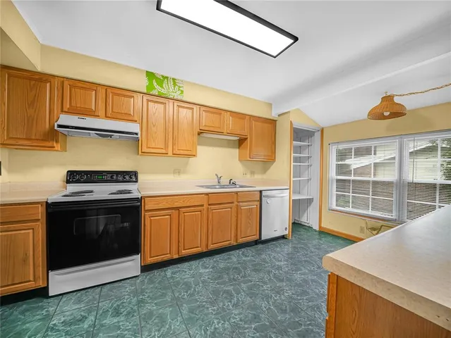 a kitchen with granite countertop a stove a sink and dishwasher