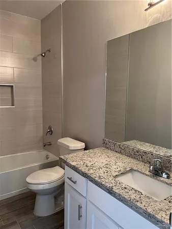 a bathroom with a granite countertop sink a toilet and shower