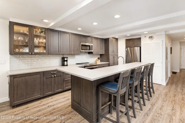 a kitchen with kitchen island a stove a sink a refrigerator and a cabinets