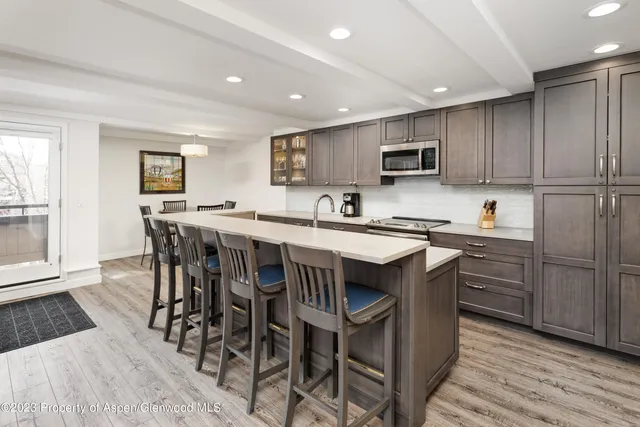 a kitchen with stainless steel appliances granite countertop a table chairs sink refrigerator and cabinets