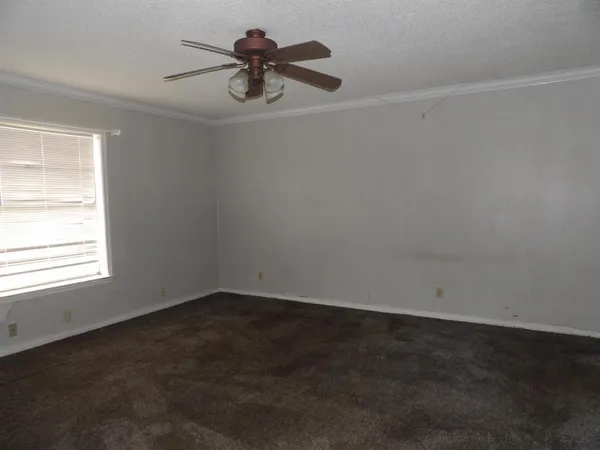 an empty room with a window and a fan