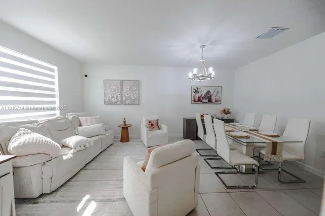 a living room with furniture a chandelier and a dining table
