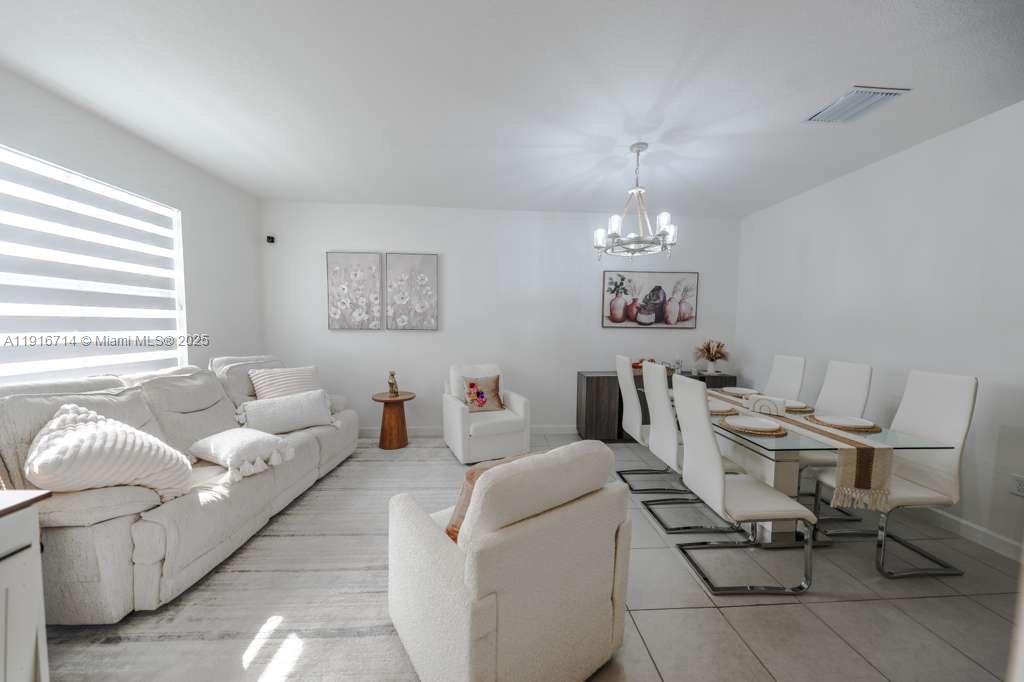 12869 Southwest 233rd Terrace Homestead, FL 33032 - Photo 5 of 30 a living room with furniture a chandelier and a dining table