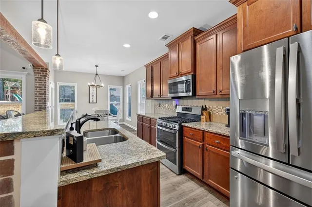 a kitchen with stainless steel appliances granite countertop a refrigerator a stove a sink a oven and a refrigerator