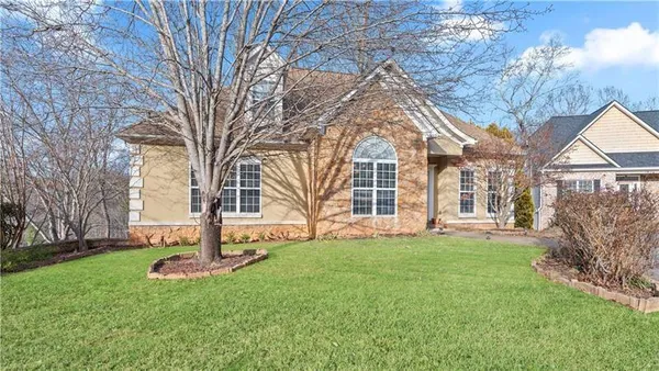 a front view of a house with a garden and trees