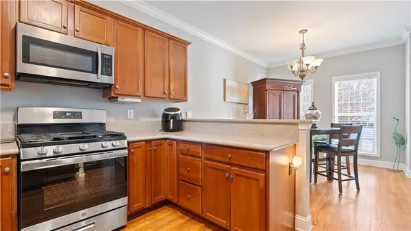 a kitchen with stainless steel appliances granite countertop wooden cabinets a stove a sink and a microwave