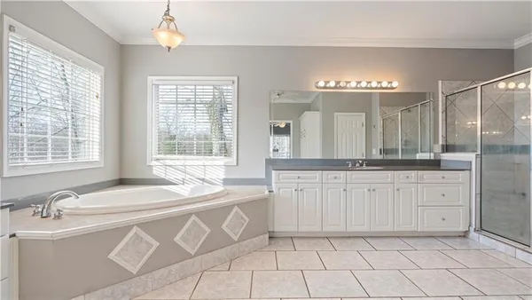a spacious bathroom with a granite countertop sink a large mirror and a bathtub