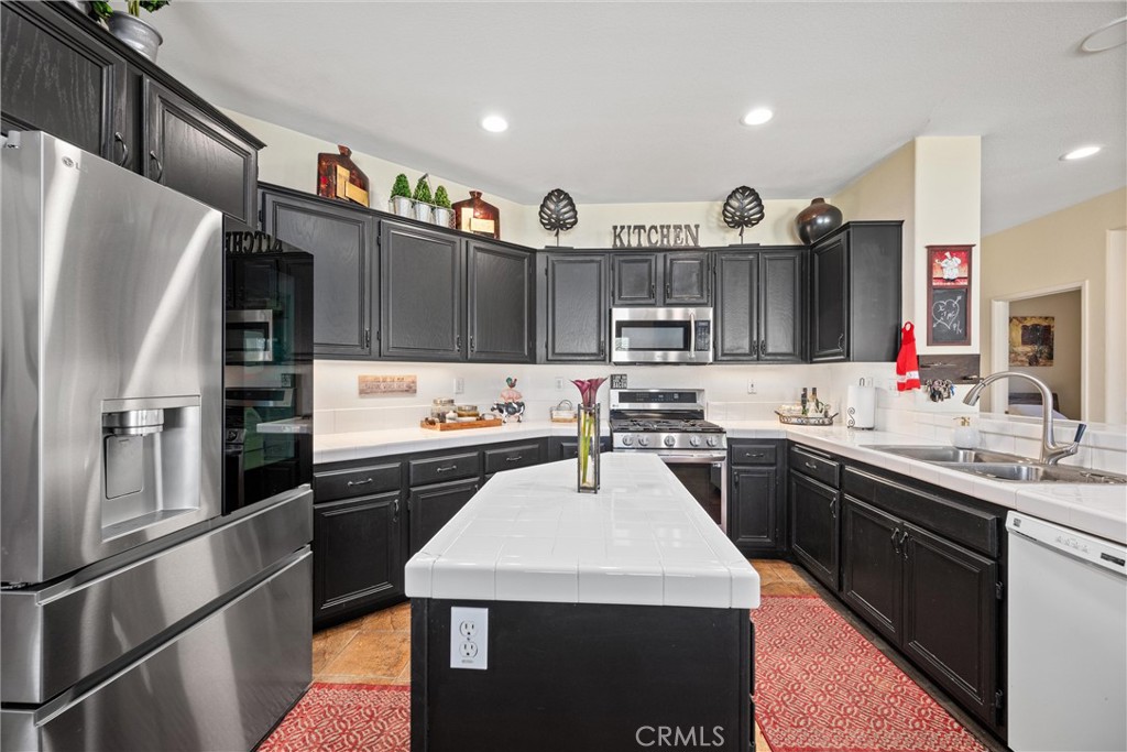 32853 Starlight Street Wildomar, CA 92595 - Photo 11 of 32 a kitchen with stainless steel appliances kitchen island granite countertop a refrigerator a sink dishwasher and a stove
