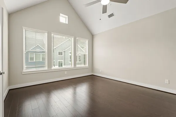 an empty room with wooden floor and windows