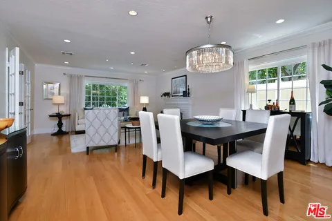 a kitchen with stainless steel appliances kitchen island a stove a sink dishwasher a refrigerator and a dining table with wooden floor