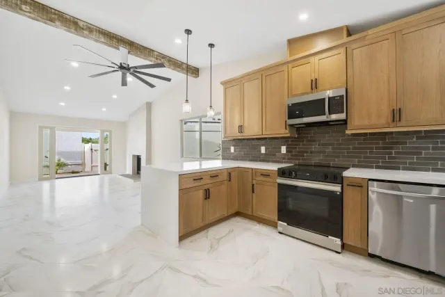 a large kitchen with stainless steel appliances granite countertop a stove a sink and a microwave