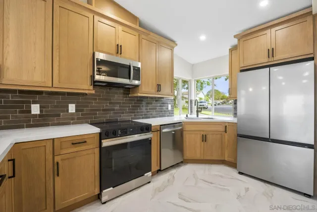 a kitchen with stainless steel appliances granite countertop a refrigerator sink stove microwave and cabinets