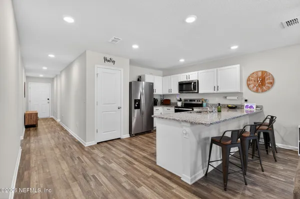 a kitchen with stainless steel appliances granite countertop a refrigerator a stove top oven a sink dishwasher and a refrigerator with wooden floor