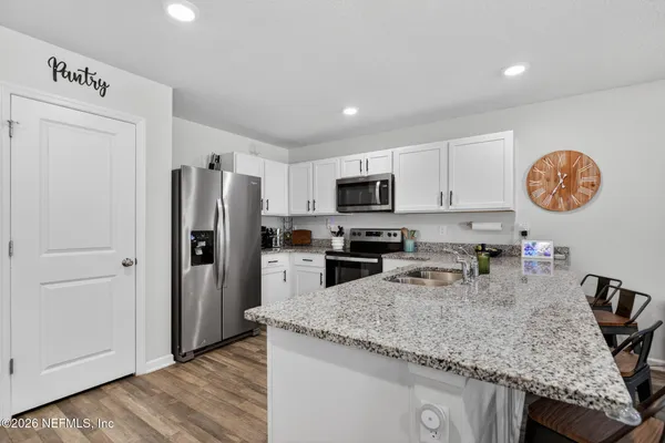 a kitchen with granite countertop stainless steel appliances a refrigerator a stove a microwave and island