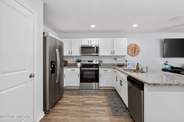 a kitchen with granite countertop a refrigerator stove top oven and sink