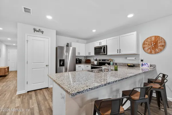 a large kitchen with granite countertop lots of counter space and stainless steel appliances