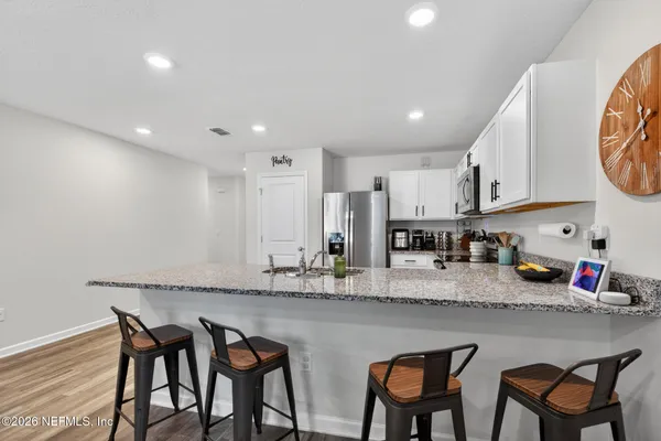 a kitchen with stainless steel appliances granite countertop a table chairs sink and cabinets