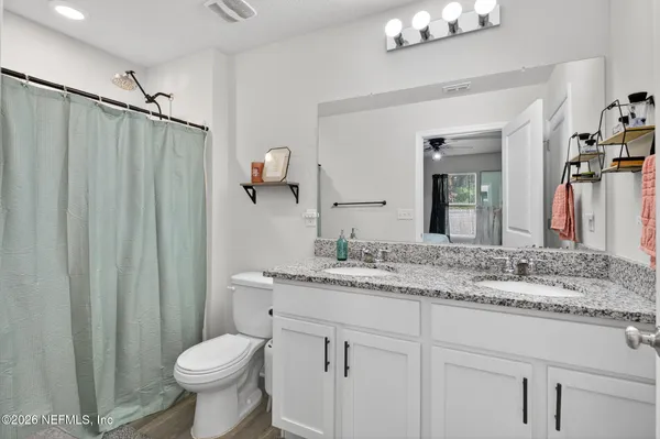a bathroom with a granite countertop sink vanity mirror and toilet