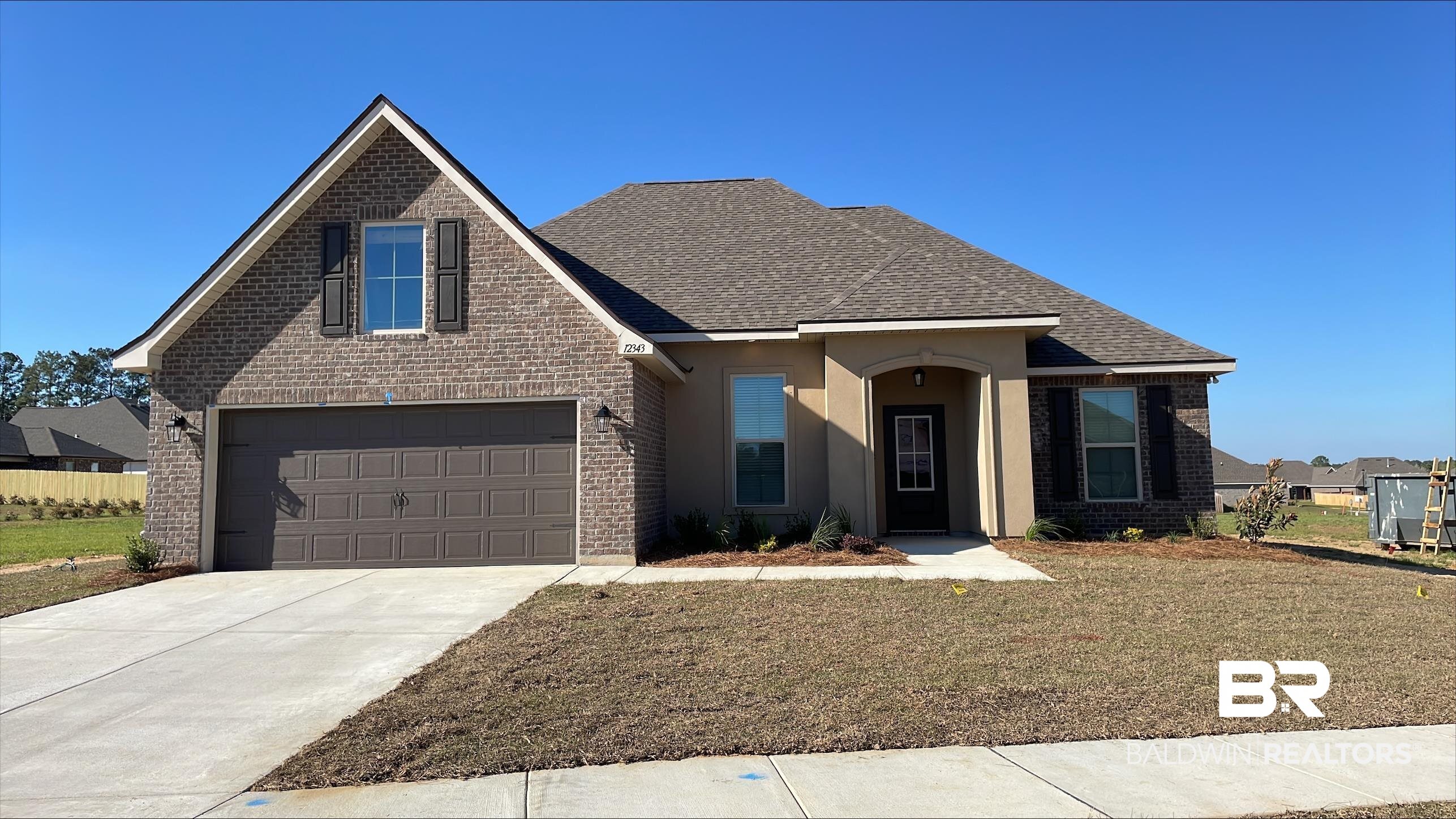 12343 Wagner Avenue Daphne, AL 36527 - Photo 1 of 3 Traditional-style home with roof with shingles, brick siding, concrete driveway, and a front yard