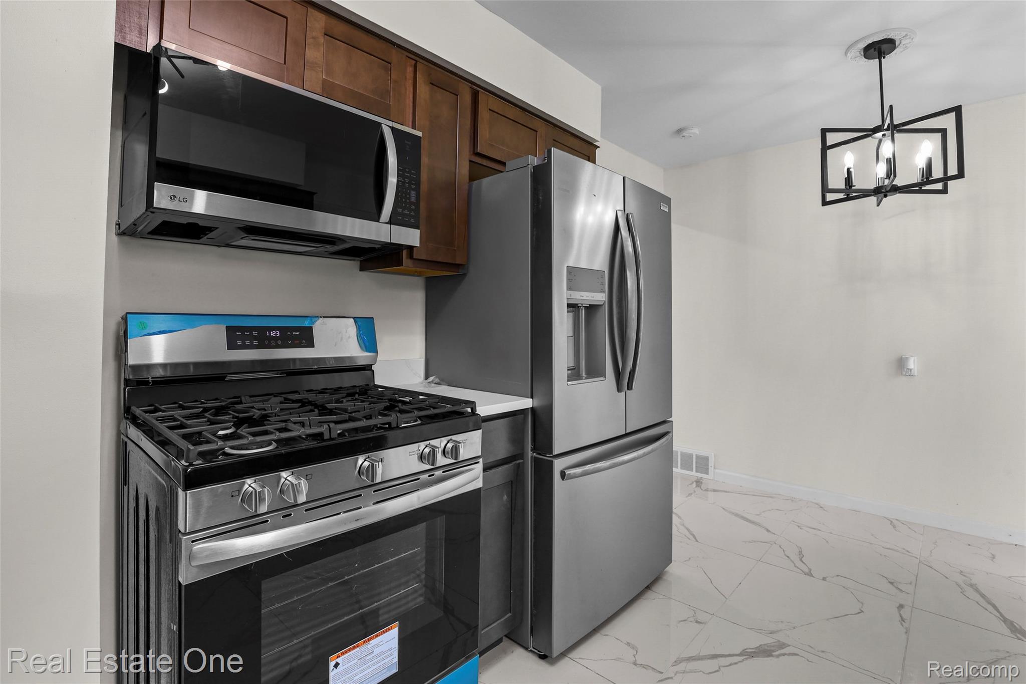 342 Melvin Street River Rouge, MI 48218 - Photo 14 of 30 Stainless steel appliances, overhead microwave, wood cabinetry, contemporary lighting fixture, and patterned tile flooring