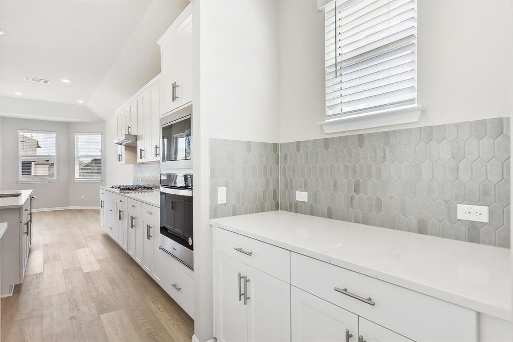 181 Old Town Road Kyle, TX 78640 - Photo 8 of 32 Elegant quartz countertops and tile backsplashes complement the spacious kitchen design.