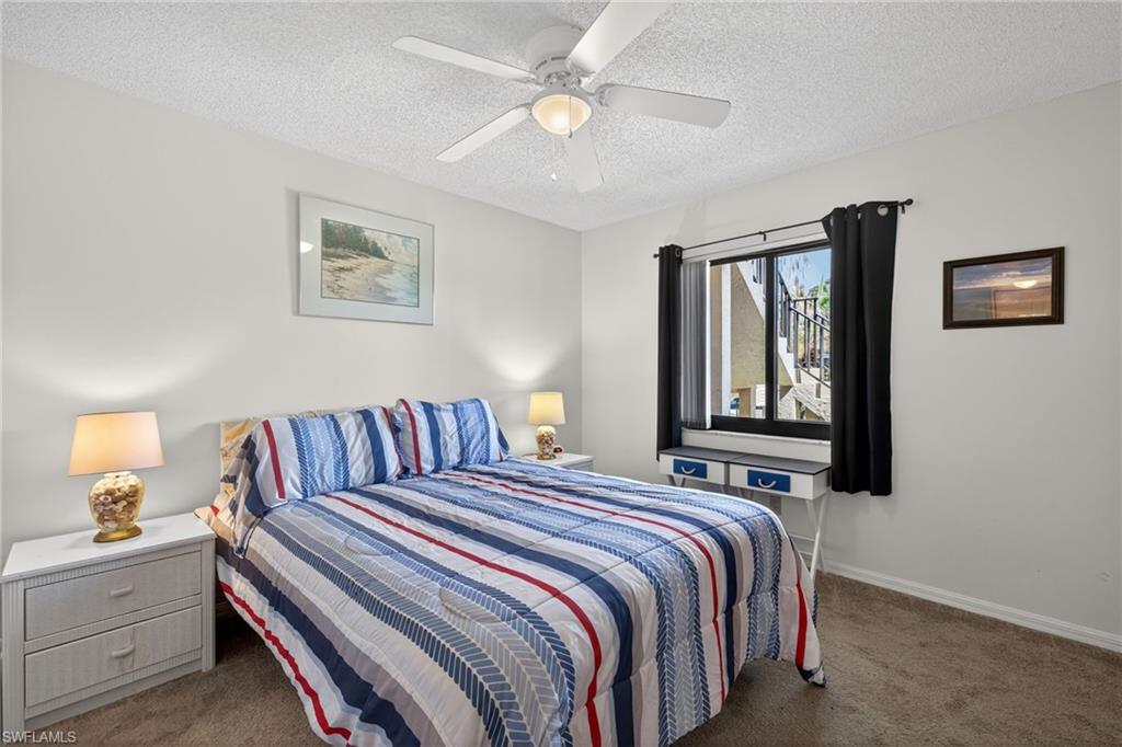 4973 Pepper Circle, Unit F105 Naples, FL 34113 - Photo 13 of 21 a bedroom with a bed and a lamp on dresser