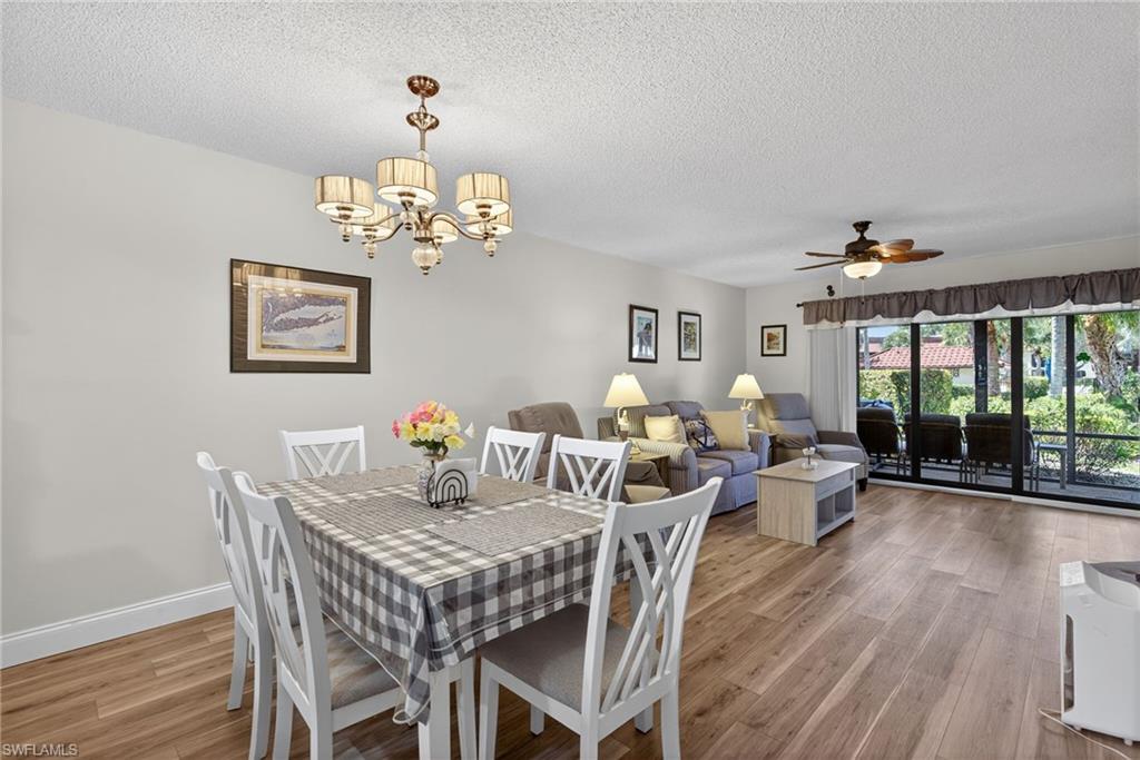 4973 Pepper Circle, Unit F105 Naples, FL 34113 - Photo 5 of 21 a view of a dining room with furniture wooden floor and chandelier