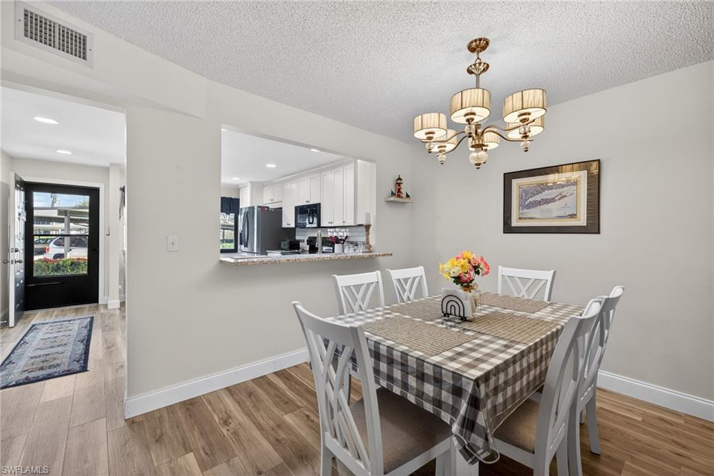 4973 Pepper Circle, Unit F105 Naples, FL 34113 - Photo 6 of 21 a view of a dining room with furniture wooden floor and chandelier