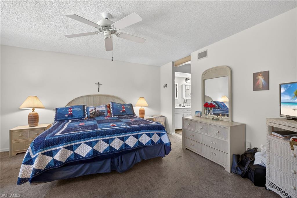 4973 Pepper Circle, Unit F105 Naples, FL 34113 - Photo 9 of 21 a bedroom with a bed and a chandelier