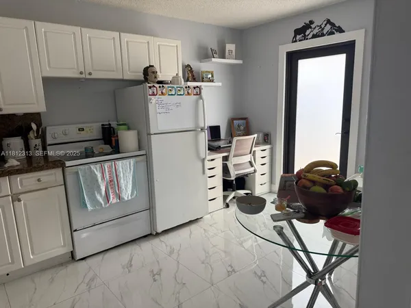 a kitchen with a refrigerator a stove and white cabinets