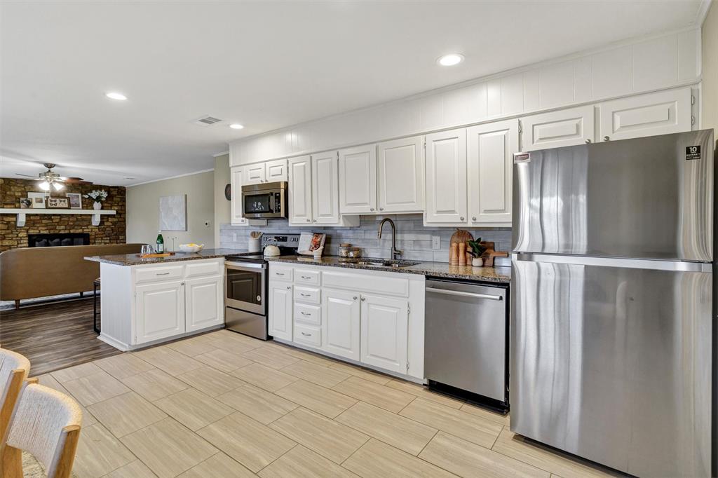1009 Russell Road Everman, TX 76140 - Photo 8 of 20 a kitchen with white cabinets stainless steel appliances and a window