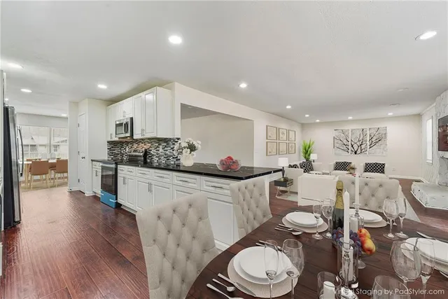 a kitchen with stainless steel appliances a dining table chairs stove and white cabinets