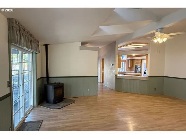 a view of kitchen and empty room with wooden floor