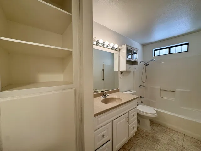a bathroom with a granite countertop sink a toilet and shower